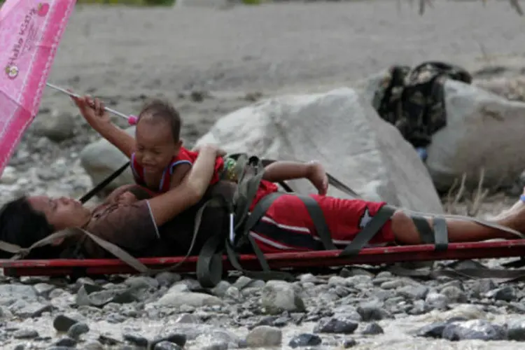 Mulher grávida que sobreviveu a enchente segura seu filho na maca, enquanto é resgatada na cidade de New Bataan, em Compostela Valley, sul das Filipinas
 (REUTERS/Erik De Castro)