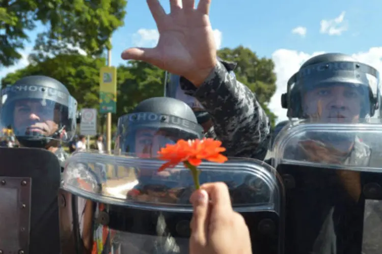Manifestante entrega flor para policial durante protesto em frente ao Estádio Nacional de Brasiília antes do início da Copa das Confederações (Marcello Casal Jr./ABr)