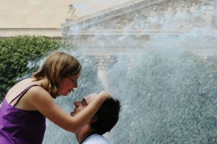 Casal refresca-se em fonte em Washington, um dos estados onde as temperaturas permanecem dentro dos padrões (Mandel Ngan/AFP)