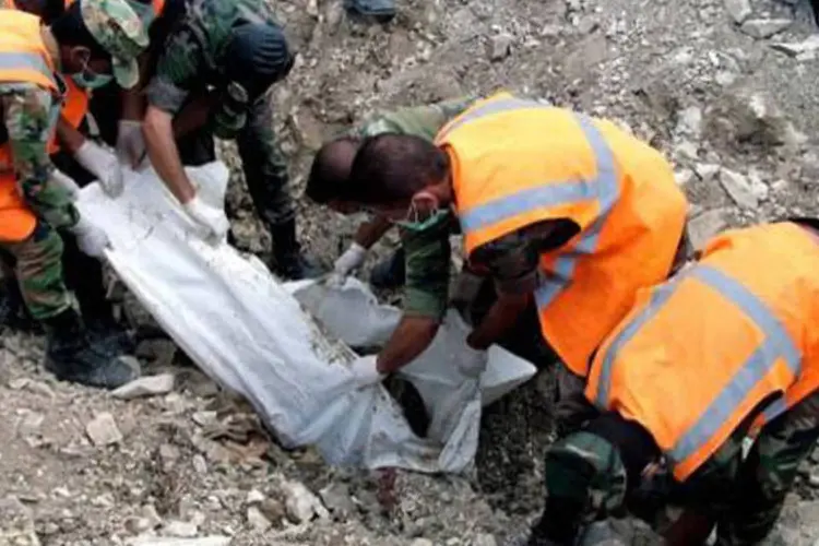 Soldados leais ao regime sírio envolvem um corpo: ONG afirmou ainda que os atos constituem crimes contra a Humanidade (AFP)