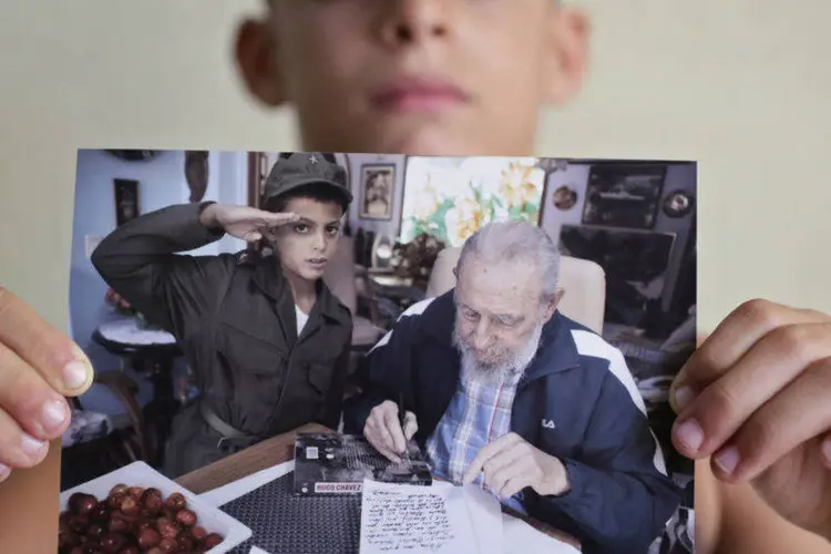 O menino Marlon Méndez segura uma foto sua com Fidel Castro (Enrique De La Osa/Reuters)
