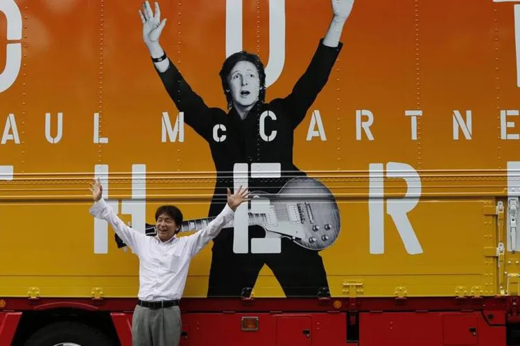 Fã tira foto em frente a painel promocional do show de Paul McCartney (Issei Kato/Reuters)