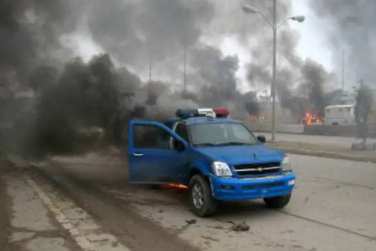 Um carro da polícia iraquiana libera fumaça após confrontos no Iraque: várias crianças e mulheres figuram entre as vítimas (Azhar Shallal/AFP)