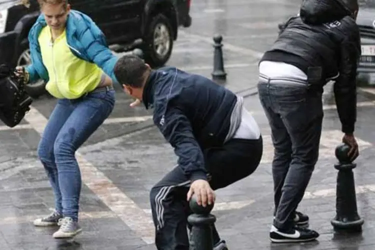Homem ajuda mulher que caiu no chão por conta dos ventos fortes no centro de Bruxelas (REUTERS)