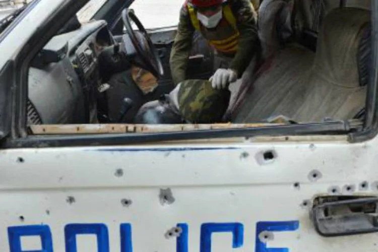 Oficial do serviço de resgate paquistanês inspeciona uma carro da polícia, depois de um tiroteio: ciclista e os agentes da polícia local foram emboscados  (A Majeed/AFP)