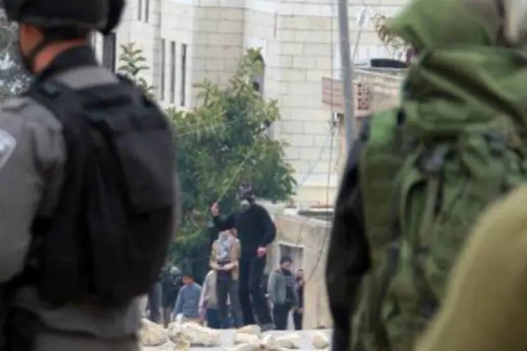 Palestinos jogam pedras em soldados israelenses: nos dias 6 e 10 de janeiro, autoridades anunciaram os programas de construção de 272 e 1.800 habitações (Jaafar Ashtiyeh/AFP)