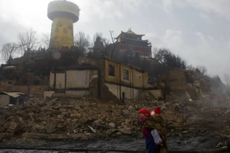 Mulher caminha em frente a casa histórica incendiada em Shangri-la: cerca de 300 casas e estabelecimentos ficaram destruídos (China Daily/Reuters)