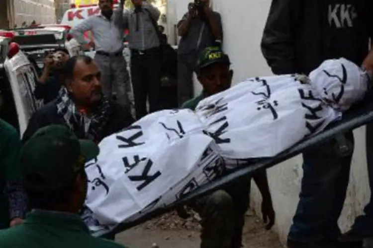 Voluntários paquistaneses carregam o corpo de uma vítima: Karachi, principal polo econômico do Paquistão, tem sido afetada há anos por conflitos (Asif Hassan/AFP)