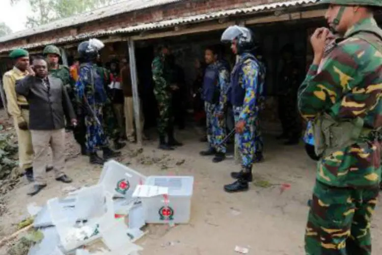 Policiais e soldados perto de urnas eleitorais danificadas: antes das eleições, a oposição pediu a renúncia do governo (AFP)