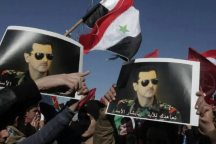 Manifestantes seguram imagens de Bashar al-Assad: foram intensificados os choques entre os jihadistas e facções islamitas contrárias ao regime de Damasco (AFP/Getty Images)