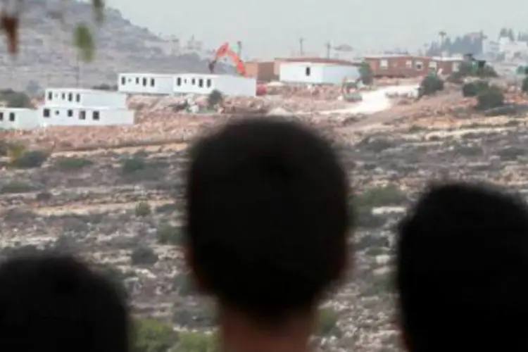 Crianças palestinas observam casas erguidas por israelenses: Israel anunciará novas construções na Cisjordânia e em Jerusalém Oriental (Abbas Momani/AFP)