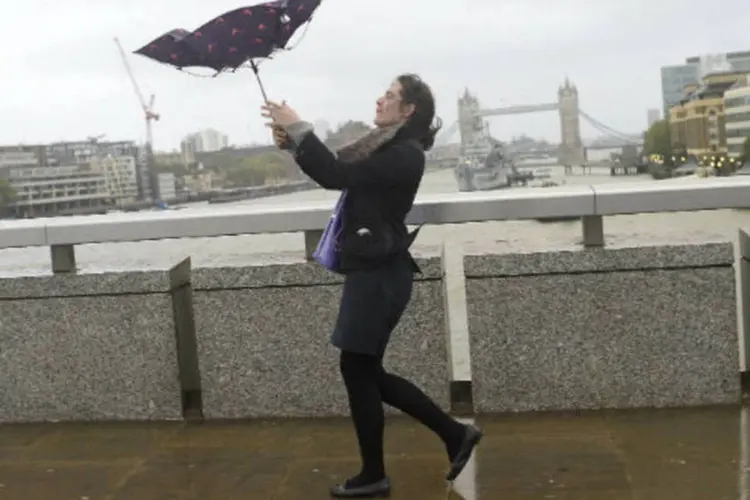 
	Mulher caminha durante chuvas em Londres: uma mulher sofreu um acidente de carro na noite de ontem provocado por uma tempestade e morreu
 (Dylan Martinez/Reuters)