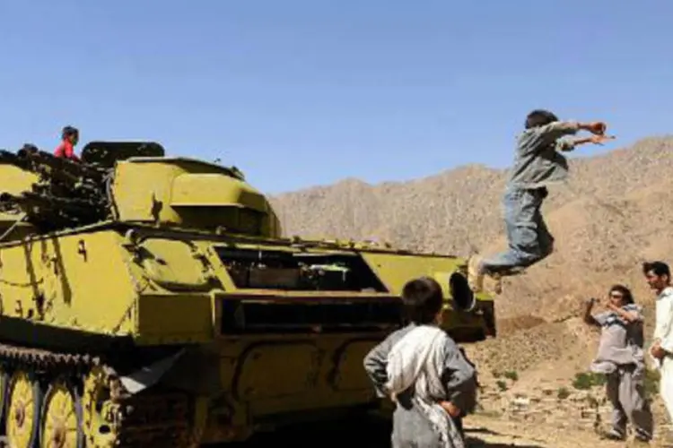 Menino afegão pula de um tanque russo destruído: governo de Barack Obama avalia submeter o russo a um julgamento militar (Shah Marai/AFP)