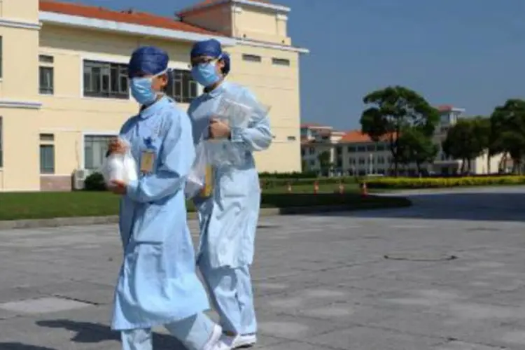 Enfermeiros caminham em frente a um hospital de Xangai: idosa visitou um mercado de aves antes de ser internada (Peter Parks/AFP)