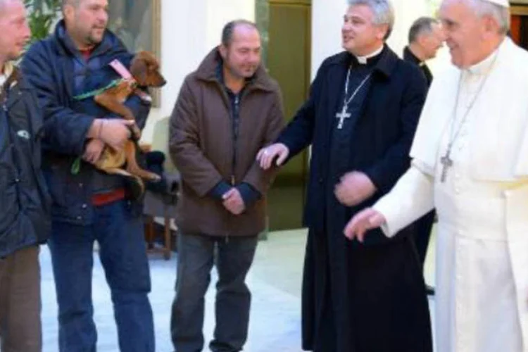 O papa Francisco conversa com o monsenhor Konrad Krajewski (2e) e três moradores de rua: pontífice iniciou este dia especial celebrando uma missa (AFP)
