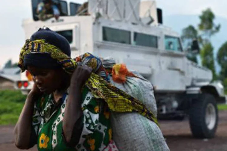 Congolesa caminha perto de um veículo militar na República Democrática do Congo: combates se prolongaram por várias horas (Carl de Souza/AFP)