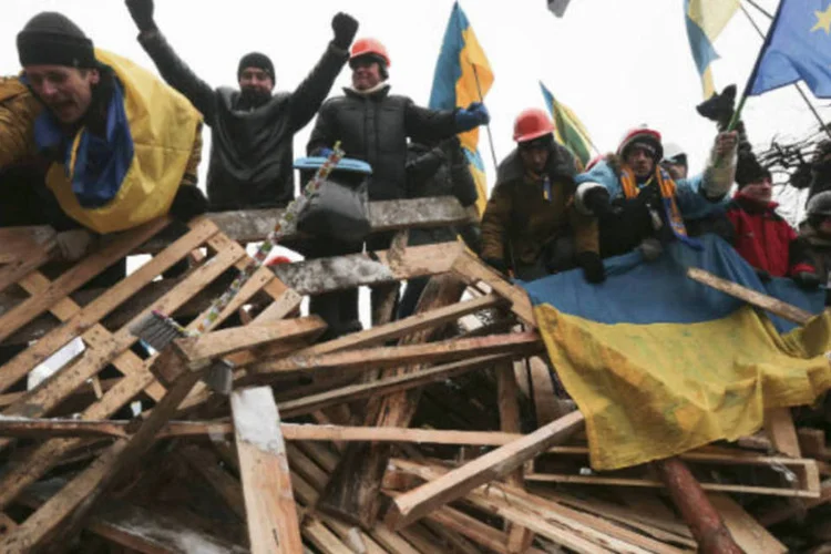 Manifestantes em barricada comemoram o recuo da polícia, na Praça Independência, em Kiev: alguns ativistas treinam para resistir aos ataques policiais (Konstantin Chernichkin/Reuters)