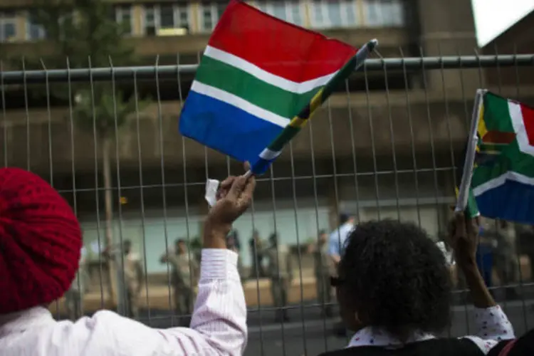 Mulheres agitam bandeiras da África do Sul: corpo do ícone Sul-africano será transportado em comboio pelas ruas de Pretória (Ronen Zvulun/Reuters)