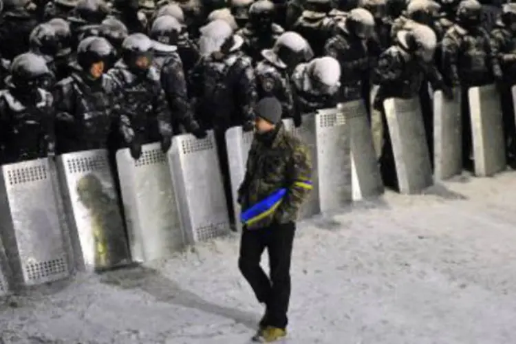 Manifestante caminha em frente à polícia que protege a sede do governo ucraniano: vários manifestantes foram agredidos com cassetetes (Viktor Drachev/AFP)