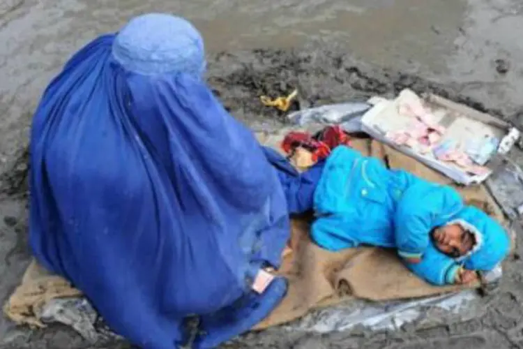 Mulher afegã pede esmolas com sua filha em meio a lama: talebans condenaram a mulher à pena de morte (AFP)