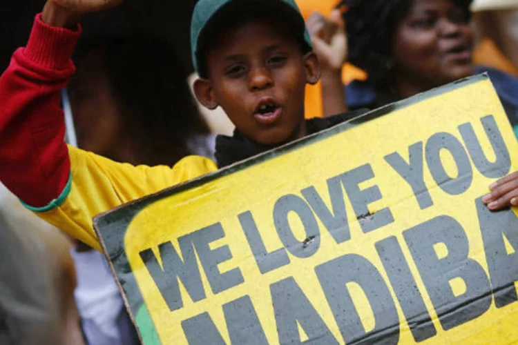 Menino com placa em homenagem a Nelson Mandela, no estádio FNB, em Johannesburgo: cerimônia conta com a presença de cerca de cem chefes de Estado (Kai Pfaffenbach/Reuters)