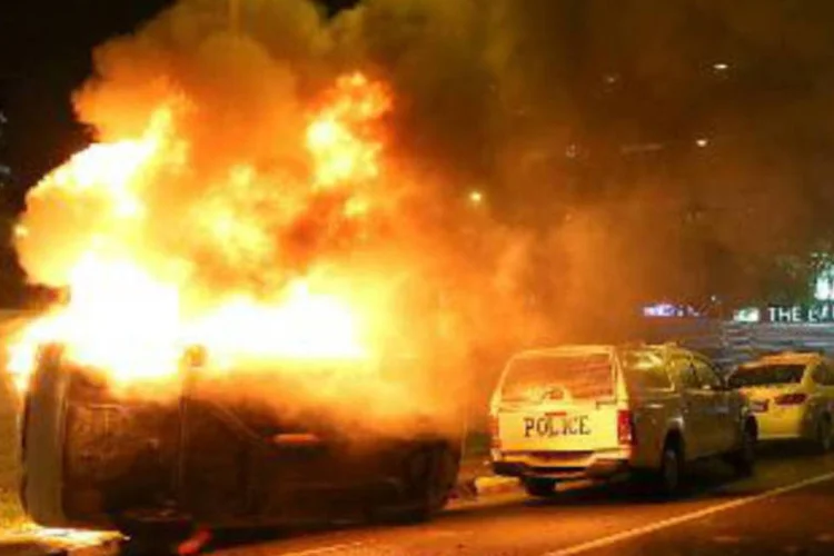 Carro da polícia em chamas, depois da ação de manifestantes em Singapura: distúrbios começaram após a morte de um indiano atropelado (Jonathan Choo/AFP)