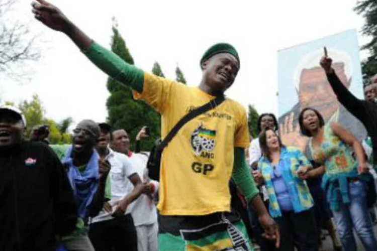 Pessoas de luto por Nelson Mandela em frente à casa do ex-presidente em Johannesburgo: entre as canções, o silêncio do luto é observado entre os fãs do herói (Stephane de Sakutin/AFP)