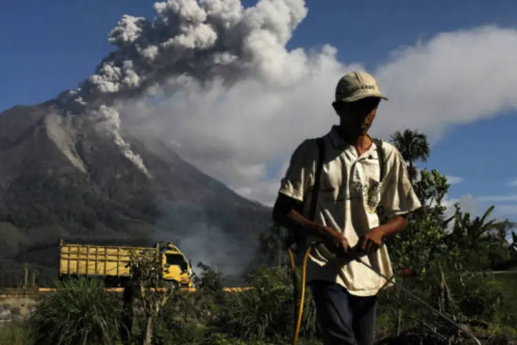 Fazendeiro na Indonésia, com o vulcão Sinabung ao fundo: 17.713 pessoas, ou 5.304 famílias de 17 povoados, foram realojadas (Beawiharta/Reuters)