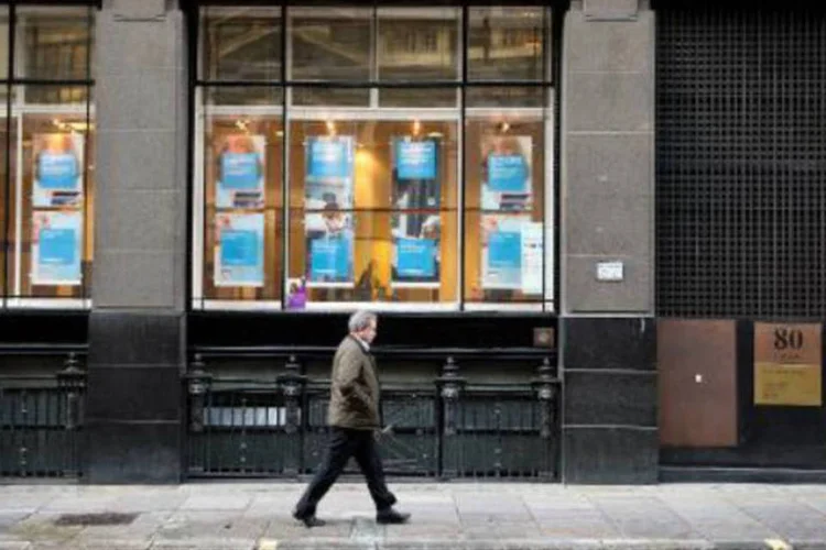Homem passa em frente a uma agência do Banco Co-operative: Paul Flowers, pastor metodista e presidente do banco, foi filmado discutindo a compra de drogas (Leon Neal/AFP)