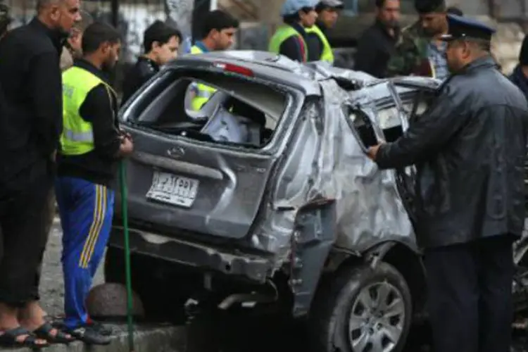 Iraquianos observam o local de um ataque com um carro-bomba: pelo menos oito explosões, incluindo sete carros-bomba, aconteceram (Ahmad Al-Rubaye/AFP)