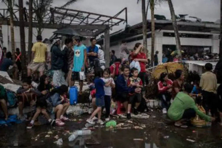 Vítimas do tufão Haiyan aguardando resgate: Inúmeras vítimas estão isoladas, sem a possibilidade de se comunicar com os seus entes queridos (Philippe Lopez/AFP)