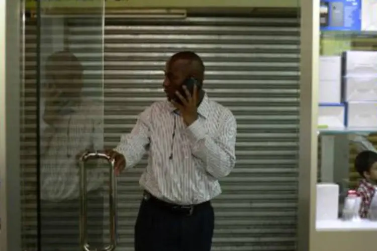 Comerciante de Guiné fala ao celular: número de assinantes únicos da região foi de 253 milhões em junho este ano e deve atingir 346 milhões até 2017 (Aaron Tam/AFP)