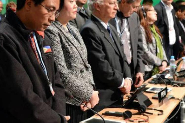 O representante das Filipinas, Naderev Sano (e), e outros delegados fazem homenagem às vítimas do tufão Haiyan: tufão deixou ao menos 10 mil mortos (Janek Skarzynski/AFP)