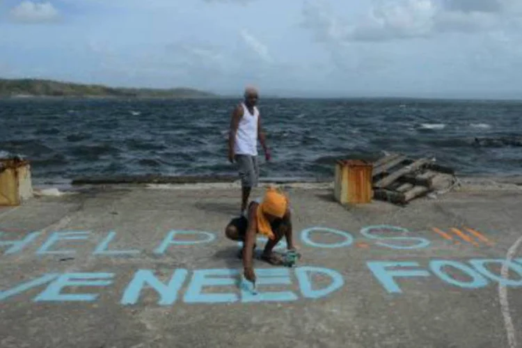 Homem pinta um pedido por comida em uma quadra de basquete, nas Filipinas: chegada da primeira ajuda de emergência neste fim de semana se viu prejudicada pelo caos (Noel Celis/AFP)