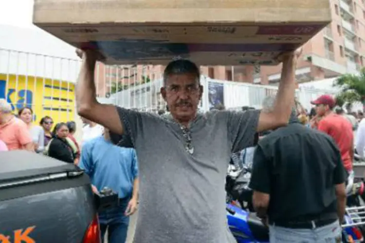 Clientes abarrotados de compras deixam uma loja de Caracas: ao mesmo tempo, Maduro prepara medidas para limitar margens de lucro (Juan Barreto/AFP)