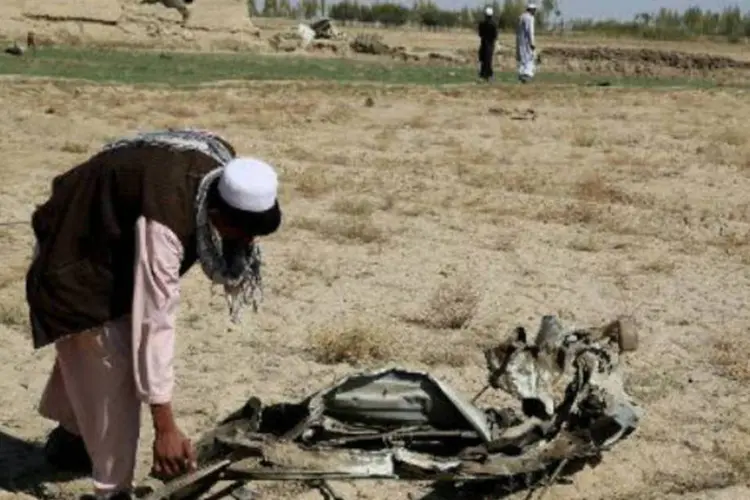 Afegão recolhe uma peça de um carro destruído por uma explosão: cinco mulheres, duas crianças e um idoso morreram na explosão (Rahmatullah Alizada/AFP)