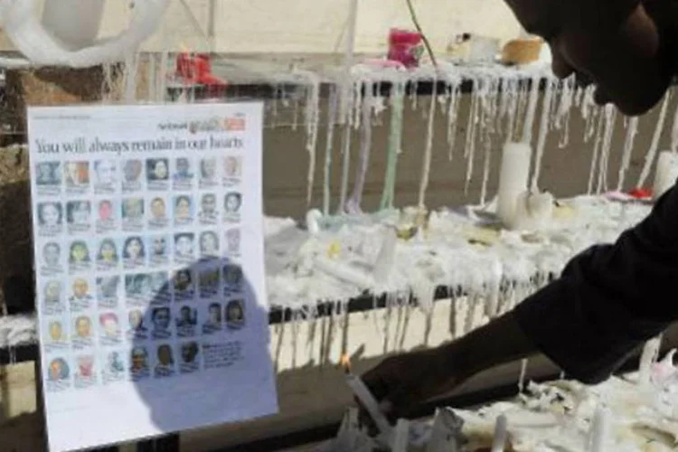 Queniano acende uma vela ao lado de uma lista de vítimas do massacre: pelo menos 67 pessoas foram mortas no ataque (Simon Maina/AFP)