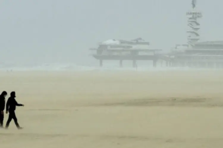 Pessoas caminham em praia durante tempestade na Holanda: ontem, as chuvas mataram duas pessoas (Getty Images)