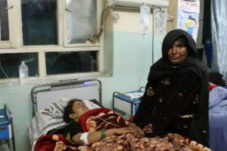 Mulher acompanha uma vítima de um atentado no Afeganistão: vítimas iam para um casamento quando o ônibus em que viajavam explodiu (Rahmatullah Alizada/AFP)