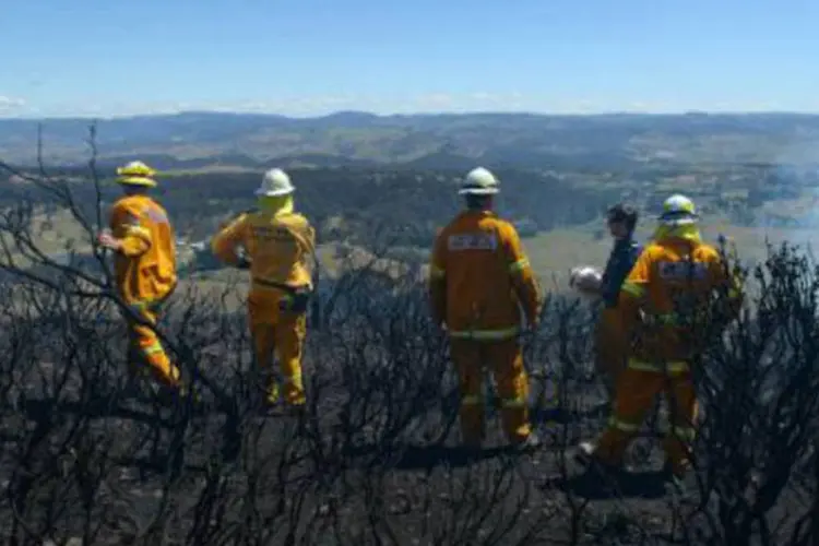 Bombeiros australianos voluntários em área do incêndio: pelo menos 65 focos seguem ativos, 18 deles fora de controle (William West/AFP)