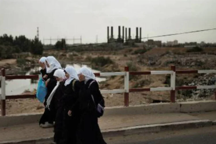 Palestinas caminham ao lado da usina de energia na Faixa de Gaza: central abastece 30% da eletricidade utilizada pelo enclave palestino dirigido pelo movimento Hamas (Marco Longari/AFP)