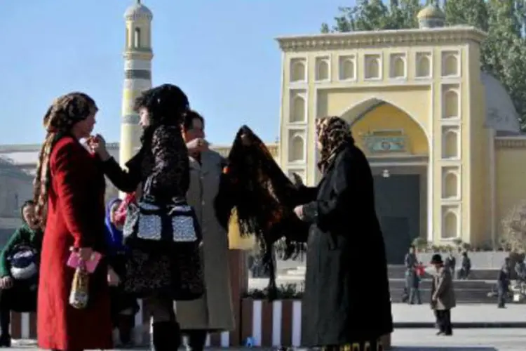 
	Mulheres uigures ao lado de uma mesquita na China: Xinjiang &eacute; tradicionalmente a terra dos mu&ccedil;ulmanos da etnia
 (Carol Huang/AFP)