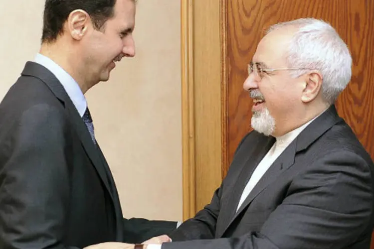 
	Bashar al-Assad com Mohammad Javad Zarif: Ir&atilde; &eacute; acusado de ter um papel ativo no conflito s&iacute;rio, algo que o que o governo de Teer&atilde; nega (SANA/Handout via Reuters)