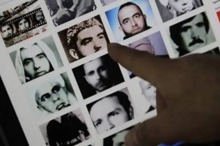 Homem mostra fotos de pessoas mortas supostamente no massacre de Hama de 1982 (Joseph Eid/AFP)