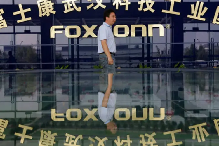 Homem caminha na frente do logotipo da Foxconn (REUTERS/Stringer)