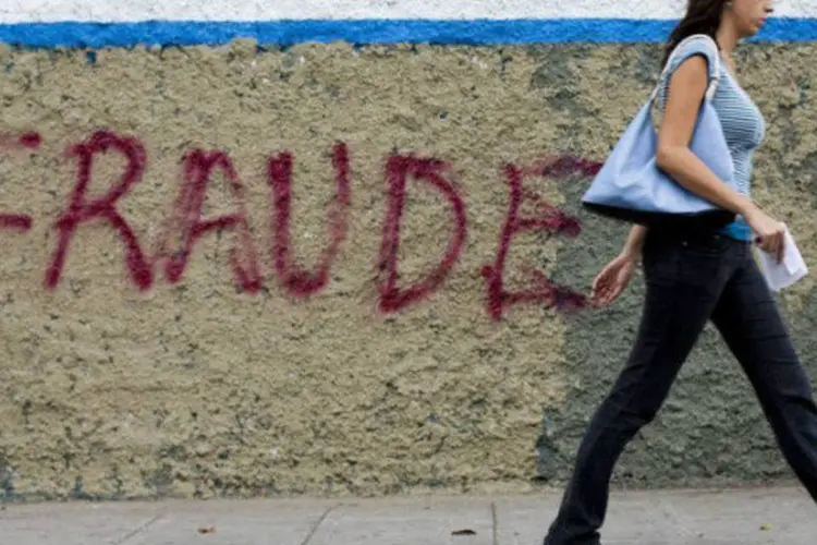 
	Mulher passa por muro com a palavra &quot;fraude&quot; escrita, em Caracas: a oposi&ccedil;&atilde;o venezuelana questiona os resultados eleitorais e denuncia fraudes na apura&ccedil;&atilde;o dos votos
 (AFP / Leo Ramírez)