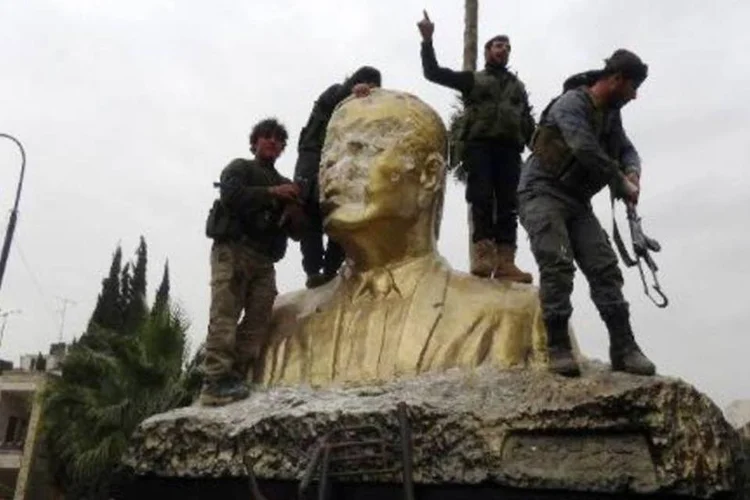 Combatentes da Frente Al-Nosra, braço sírio da Al-Qaeda, atacam estátua do falecido presidente sírio Hafez al-Assad (Sami Ali/AFP)