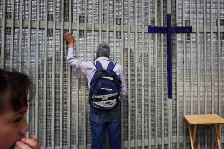 Homem fala com familiares através de fronteira que separa EUA do México, em Tijuana (Sandy Huffaker/AFP)