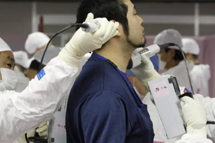 Funcionário é escaneado por radiação ao entrar no centro de operações de emergência da Tepco na usina nuclear de Fukushima: descobriu-se partículas em seu corpo (Issei Kato/Reuters)
