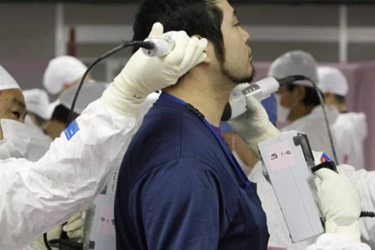 Funcionário é escaneado por radiação ao entrar no centro de operações de emergência da Tepco na usina nuclear de Fukushima: descobriu-se partículas em seu corpo (Issei Kato/Reuters)
